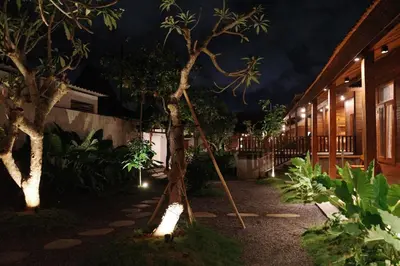 a courtyard at night with a tree and lights at The Riang Villa in Kerobokan