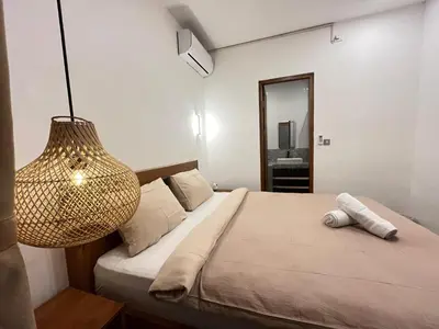 a bedroom with a bed with a lamp and a mirror at Della Rossa in Seminyak