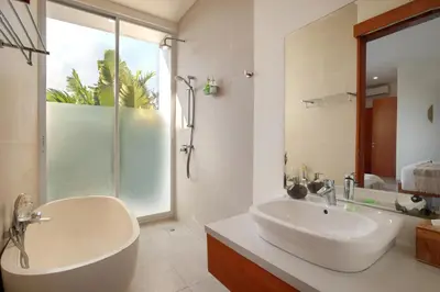 a bathroom with a tub and a sink and a shower at Villa Indaros in Seminyak