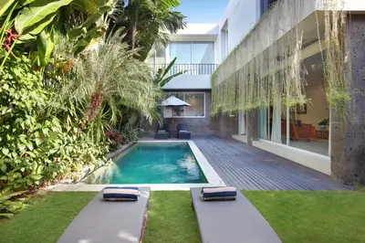 a swimming pool with two loungers in a yard at Villa Indaros in Seminyak