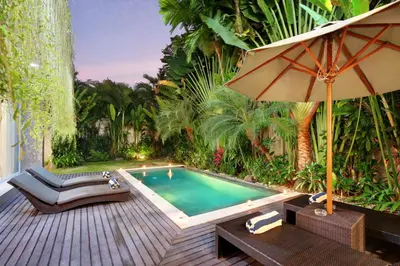 a backyard with a pool and an umbrella and a table at Villa Indaros in Seminyak