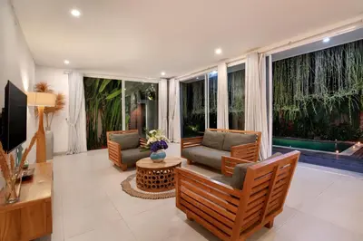 a living room with two chairs and a television at Villa Indaros in Seminyak