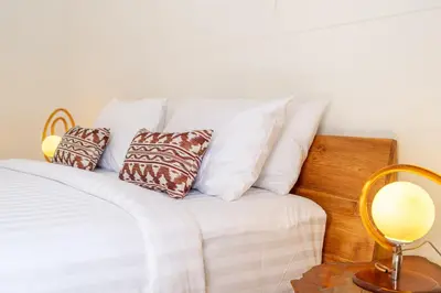 a white bed with pillows and a table with a lamp at QLO Villa , Seminyak in Seminyak