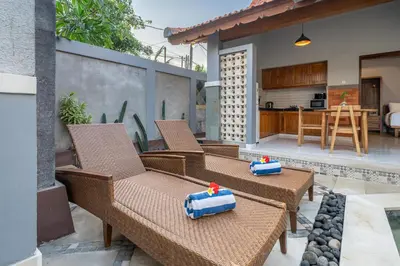 a patio with wicker chairs and a kitchen at Q LA Villas in Seminyak