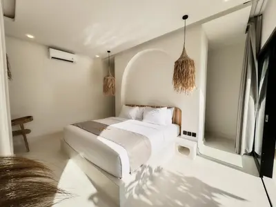 a white bedroom with a bed and a mirror at Armonia Bali Legian Villas in Legian