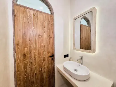 a bathroom with a wooden door and a sink at Armonia Bali Legian Villas in Legian