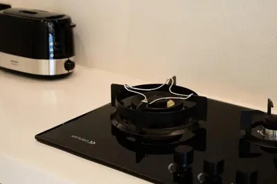 a black stove top on a counter with a coffee maker at Armonia Bali Legian Villas in Legian