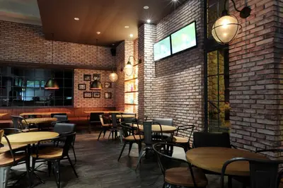 a restaurant with tables and chairs and a brick wall at Mahogany Hotel in Nusa Dua