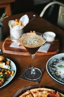 a drink sitting on a table with plates of food at Mahogany Hotel in Nusa Dua
