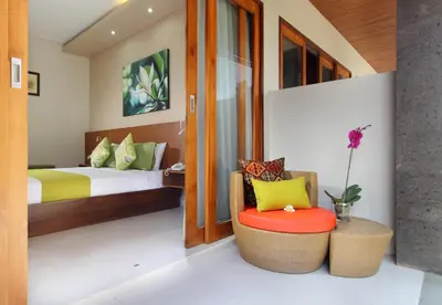 a bedroom with a bed and a chair in a room at Kubu Cempaka Seminyak in Seminyak