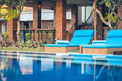 two blue lounge chairs next to a swimming pool at Kubu Cempaka Seminyak in Seminyak