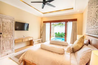 a bedroom with a bed and a tv and a window at Villa Mayo in Legian