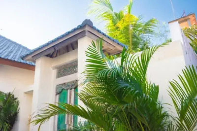 a building with a palm tree in front of it at Villa Mayo in Legian