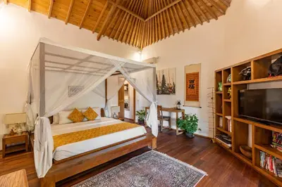 a bedroom with a canopy bed and a tv at Villa Tago - 5 BR Villa in Umalas in Kerobokan