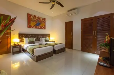 a bedroom with two beds and a ceiling fan at ViLLA GREEN MANGO SEMINYAK BALI in Seminyak