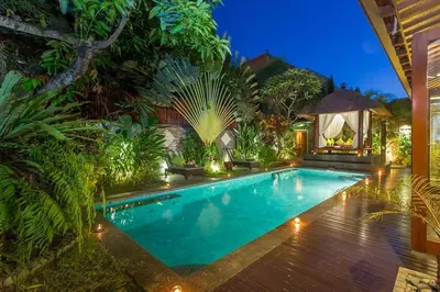 a swimming pool in a garden at night at ViLLA GREEN MANGO SEMINYAK BALI in Seminyak