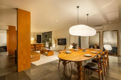 a dining room and living room with a wooden table at The Fernweh Umalas in Canggu