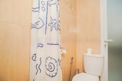 a bathroom with a toilet and a shower curtain at Fun Living Guest House in Seminyak
