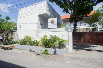 a white building with a sign on the side of it at Fun Living Guest House in Seminyak