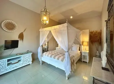 a bedroom with a canopy bed and a television at Frangipani Villa Seminyak - 2BR Pool Walk to Beach in Seminyak