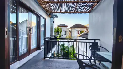 a balcony with chairs and a table and some windows at Villa by BALIem in Jimbaran
