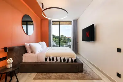 a bedroom with a bed with an orange wall at Alex Villas Complex N5 in Canggu
