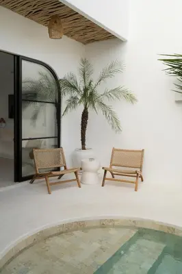 a patio with two chairs and a palm tree at Villa Casa Gaia 5 by BaliSuperHost in Kerobokan