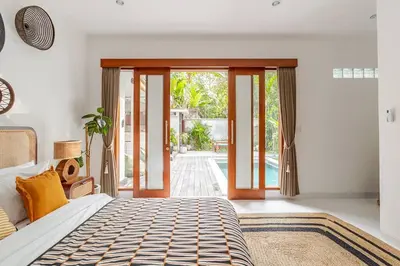 a bedroom with a bed and sliding glass doors at Villa Aliran - Modern Comfort in tranquil Umalas in Canggu