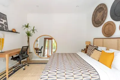 a bedroom with a bed and a desk and a mirror at Villa Aliran - Modern Comfort in tranquil Umalas in Canggu