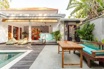 a patio with a wooden table and benches next to a house at Villa Aliran - Modern Comfort in tranquil Umalas in Canggu