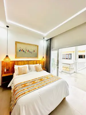 a bedroom with a large white bed with a painting on the wall at Tirta Mumbul Villa in Badung