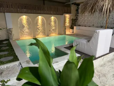 a swimming pool in a villa with a chair at Tirta Mumbul Villa in Badung
