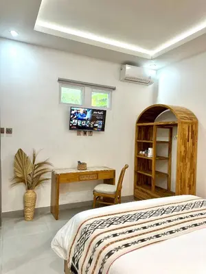 a bedroom with a bed and a desk and a tv at Tirta Mumbul Villa in Badung