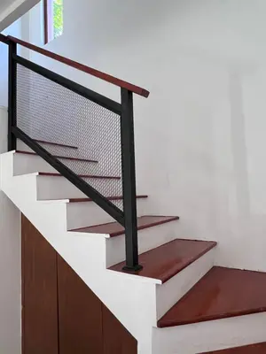 a staircase with a black rail and wood treads at Louise villa in Jimbaran