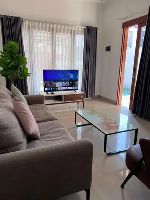 a living room with a couch and a glass coffee table at Louise villa in Jimbaran
