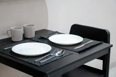 a black table with white plates and silverware on it at Bali Bustle Sunset Coliving and Coworking Space in Legian