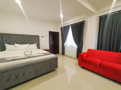 a bedroom with a bed and a red couch at Carstenzs Home Kuta in Kuta