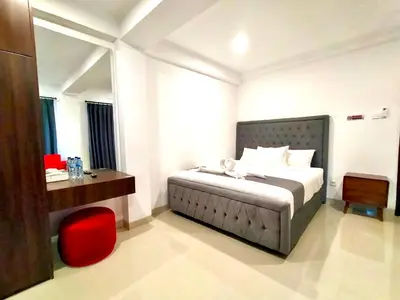a bedroom with a bed and a red chair at Carstenzs Home Kuta in Kuta