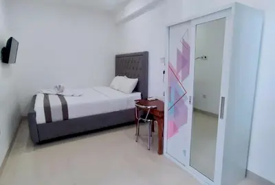 a bedroom with a bed and a table and a glass door at Carstenzs Home Kuta in Kuta