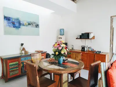 a room with a table with a vase of flowers on it at The Decks Bali in Legian