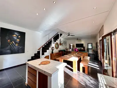 a living room with a table and a staircase at The Getaway Villa Seminyak Bali in Seminyak
