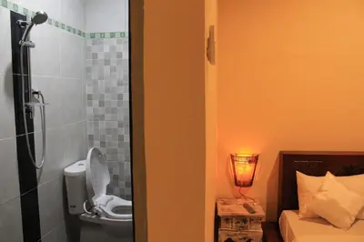 a bathroom with a shower with a toilet and a sink at Chillin Kuta Homestay in Kuta
