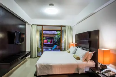 a hotel room with a bed and a television at Kuta Reef Apartments in Kuta