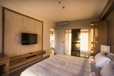 a bedroom with a large bed with a tv on the wall at Kuta Reef Apartments in Kuta