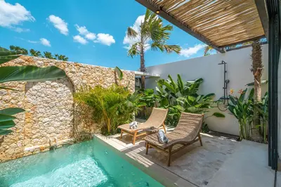 a patio with two chairs and a swimming pool at Casa Vera - Delightful 1-Bedroom Villas in the Heart of Umalas in Canggu
