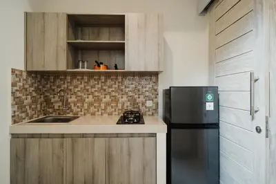 a kitchen with a black refrigerator and a sink at D'Leafy Seminyak in Seminyak