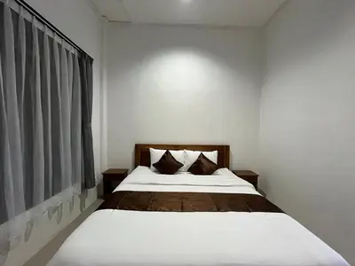 a bedroom with a bed with white sheets and a window at Kubu Celagi Manis in Jimbaran
