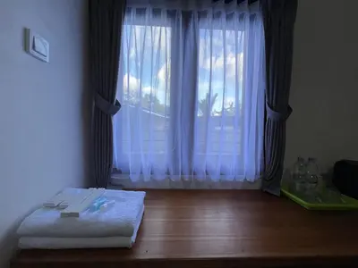 a room with a large window with white curtains at Kubu Celagi Manis in Jimbaran