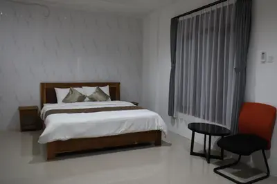 a bedroom with a bed and a chair and a window at Kubu Celagi Manis in Jimbaran