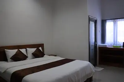 a bedroom with a large white bed and a window at Kubu Celagi Manis in Jimbaran